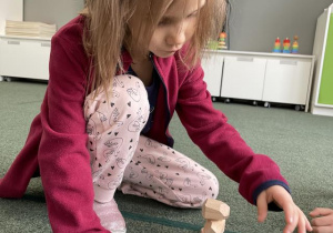dziecko buduje wieżę z klocków o wielu podstawach- doskonalenie logicznego myślenia, koordynacji i koncentracji